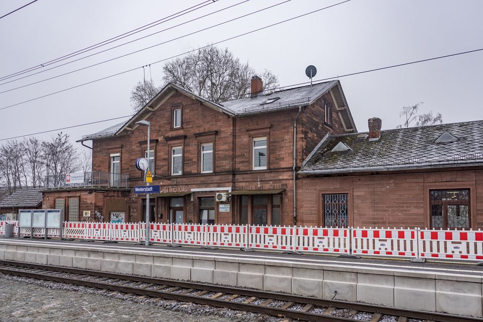 Auf dem Foto ist der Weiterstädter Bahnhof zu sehen und die rot-weißen Absperrungen, die ein Geländer ersetzen.